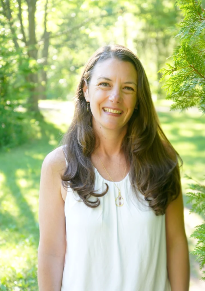 smiling woman with white shirt and green trees in the background